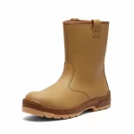 Ein freigestellter, beigefarbener Sicherheitsstiefel (Schlupfstiefel) auf weißem Hintergrund. Der Stiefel verfügt über ein robustes Obermaterial mit verstärkten Nähten, zwei Anziehschlaufen am oberen Schaftrand und eine dicke, braun abgesetzte Profilsohle für festen Stand auf Baustellen.